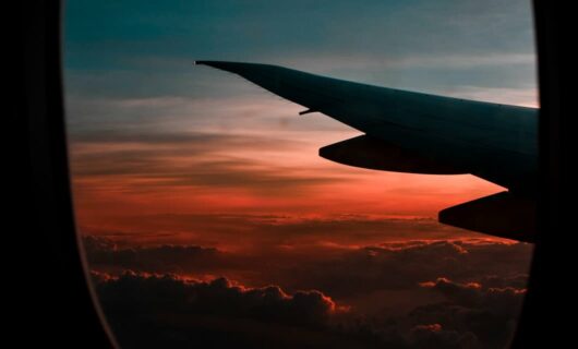 View of dark sunset and plane wing out plane window